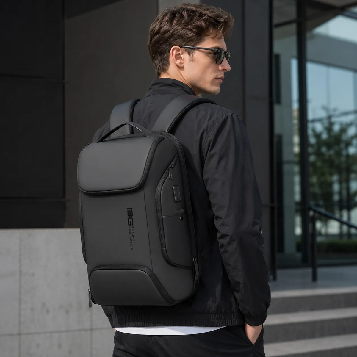 Homme portant un sac à dos ordinateur BG Future Aesthetics noir dans un environnement urbain moderne
