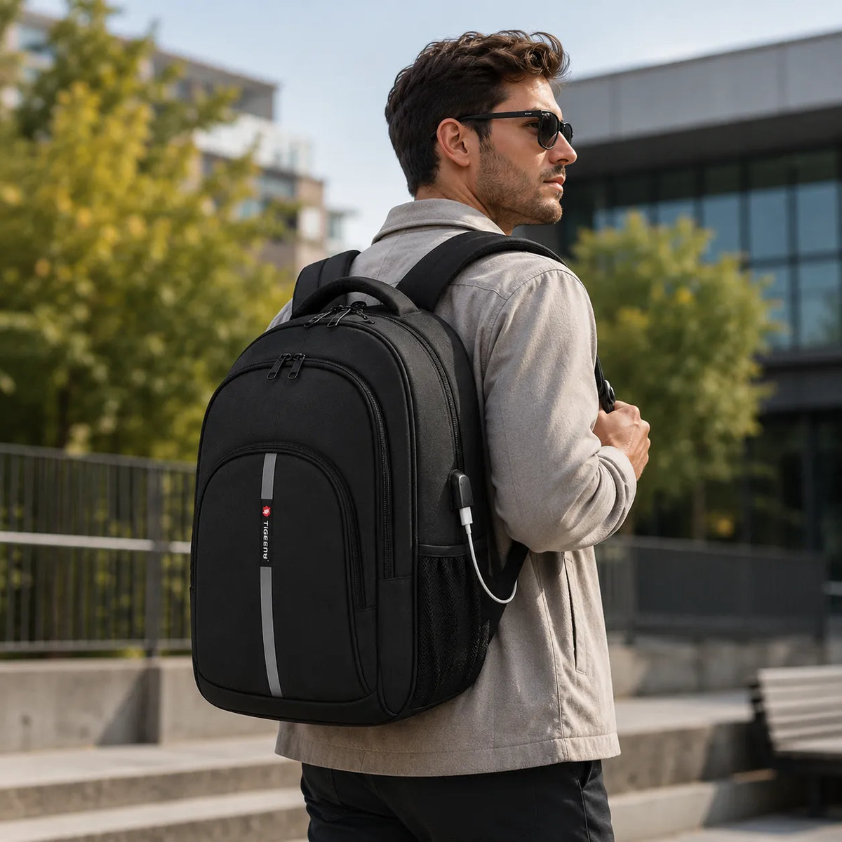 Homme portant un sac a dos ordinateur noir TIGERNU dans un environnement urbain moderne
