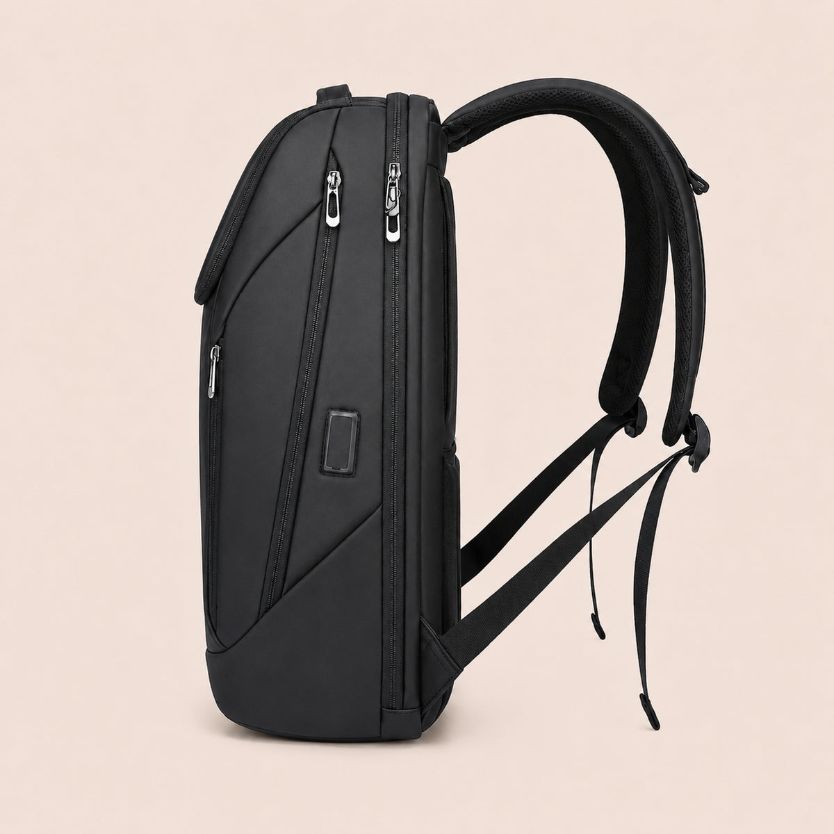 Vue latérale d’un sac à dos ordinateur noir avec compartiments zippés et design structuré sur fond beige clair
