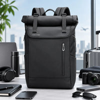 Le Nomade, sac à dos ordinateur Roll Top noir présenté avec des accessoires de voyage