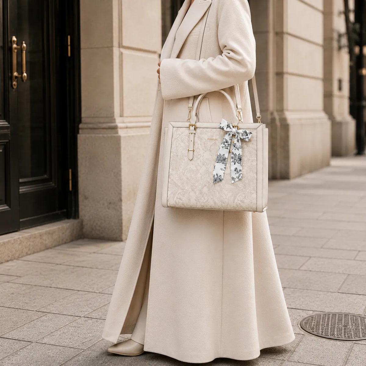 Sac ordinateur femme blanc porté avec longue veste beige en environnement urbain