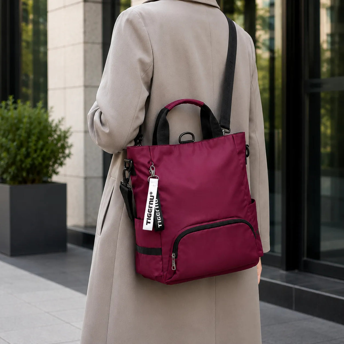 Sac ordinateur femme prune TIGERNU porté avec une veste longue professionnelle, silhouette discrète et style élégant pour un usage quotidien.