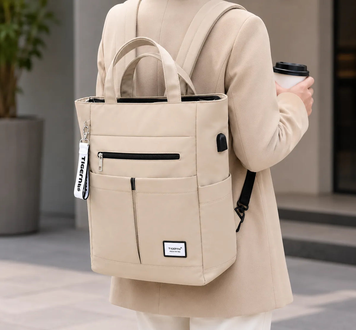 Sac ordinateur femme beige porté en sac à dos avec tenue longue et silhouette discrète, style élégant pour le quotidien professionnel.